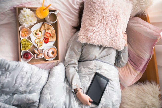 Charming female texting on her tablet after waking up