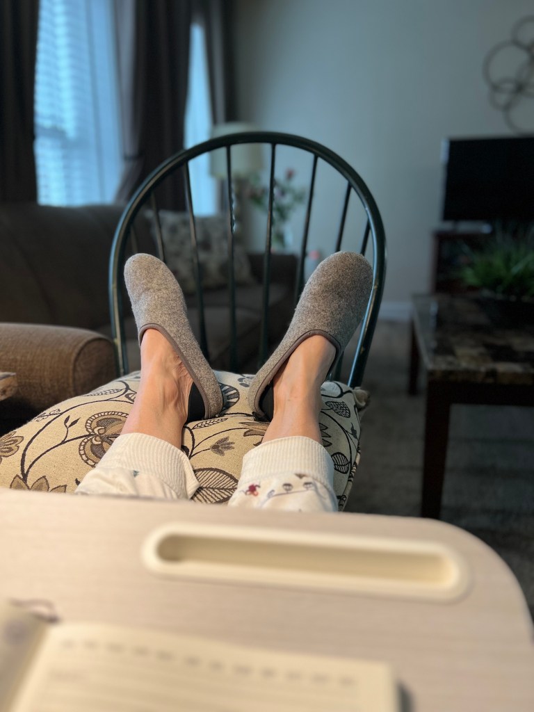 Feet in slippers propped up on a chair.