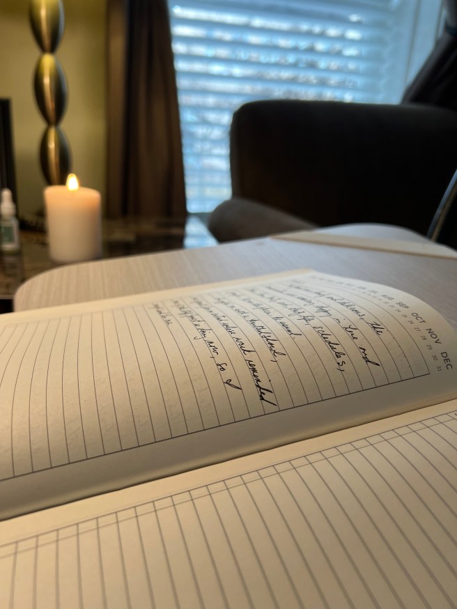 A lined notebook with writing and a candle